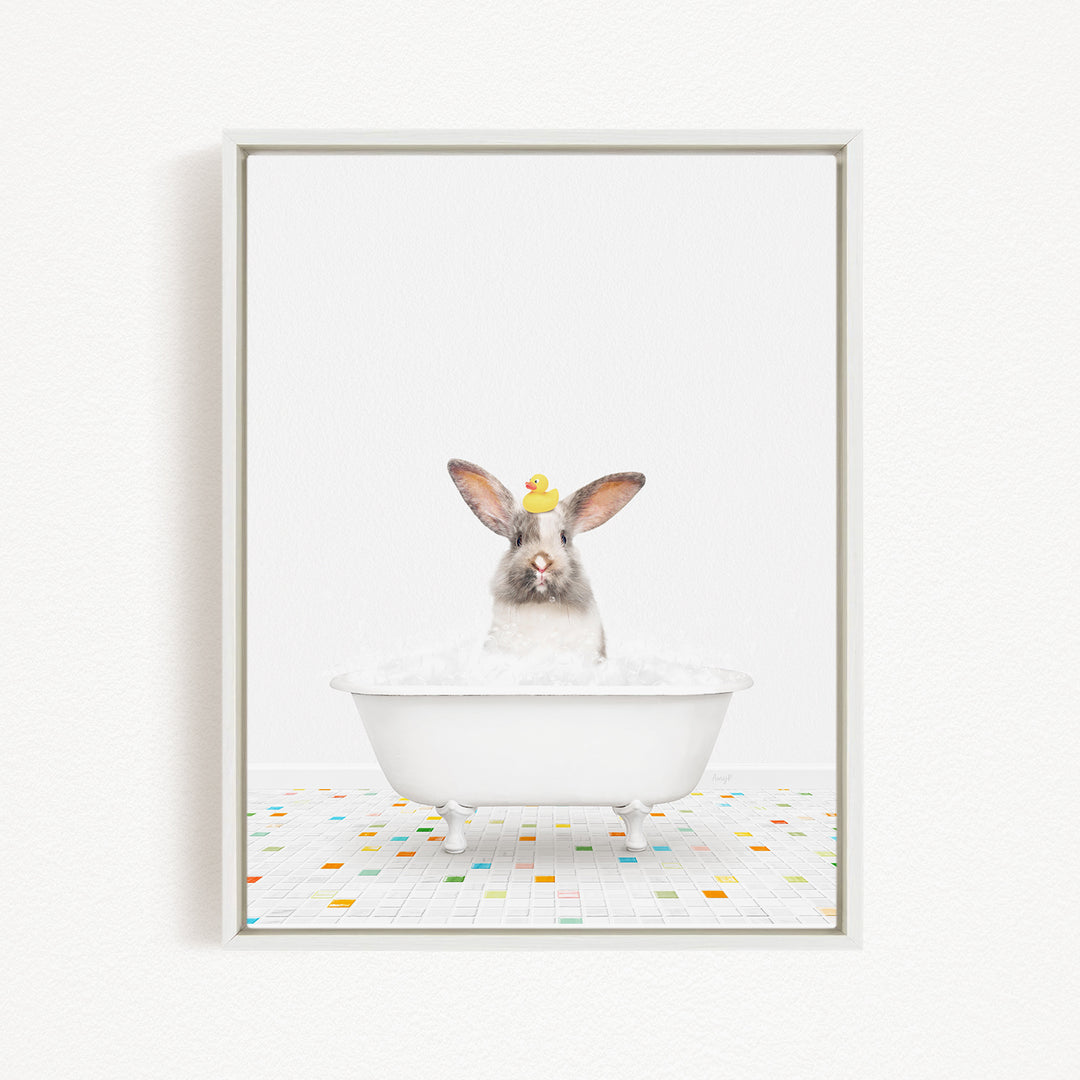 A white rabbit sitting in a white bathtub filled with bubbles, with a yellow rubber duck perched on its head.