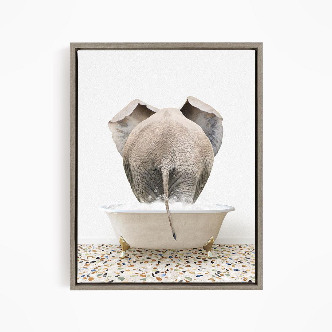 A gray elephant is standing in a white bathtub filled with water, with its trunk submerged in the water.