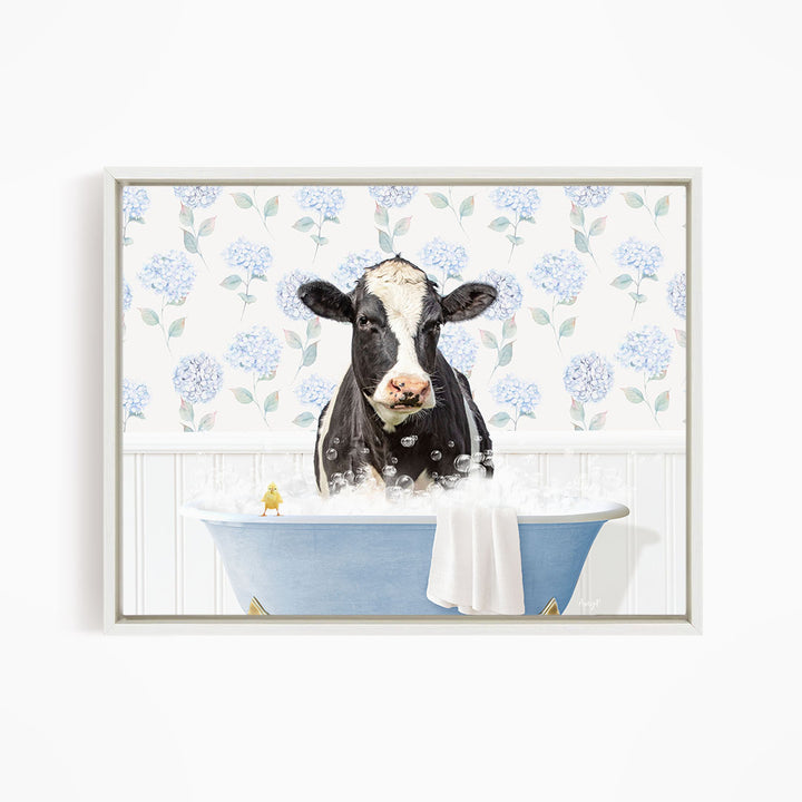 A black and white cow is sitting in a blue bathtub filled with bubbles, with a yellow bird perched on the edge of the tub.