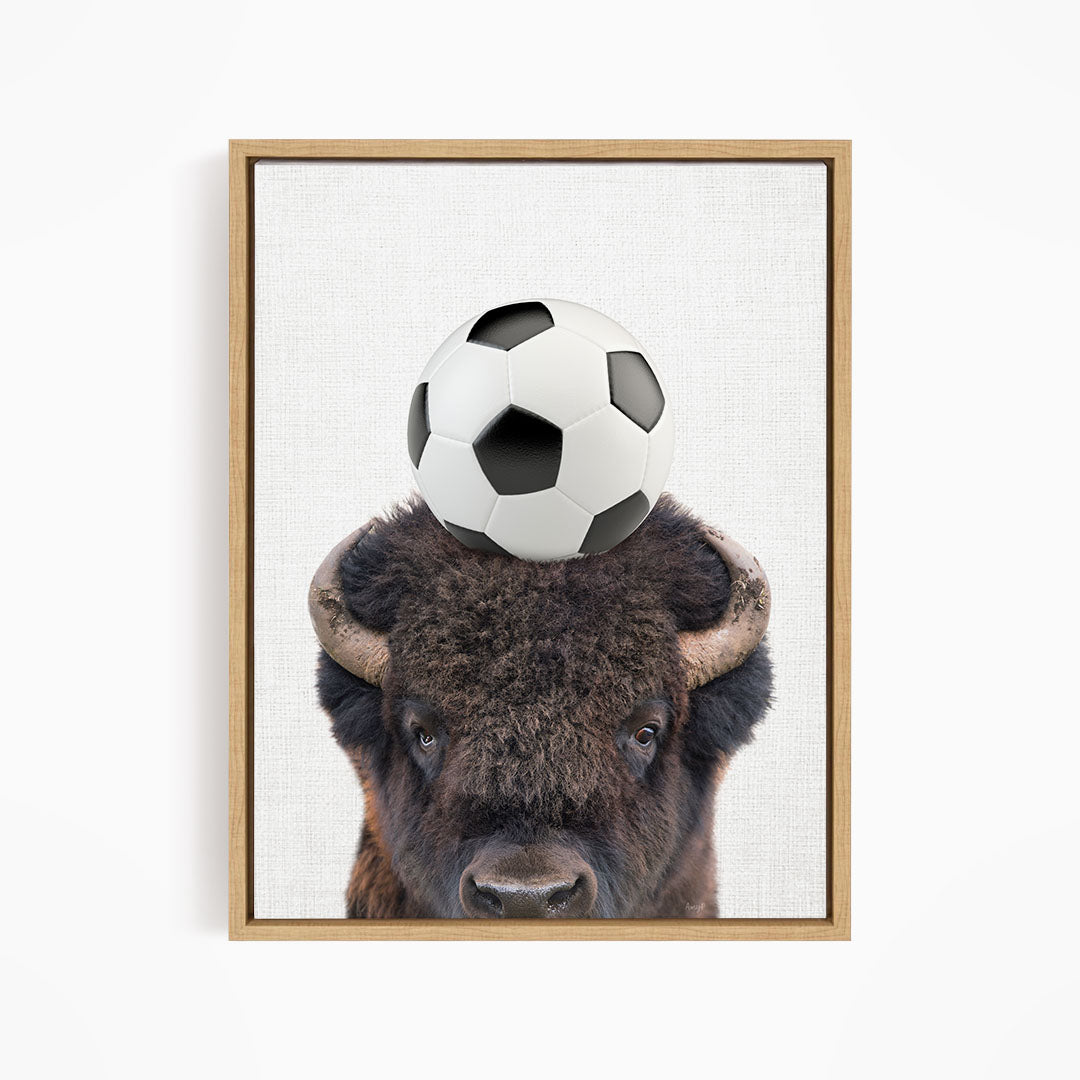 A buffalo with a soccer ball on its head.