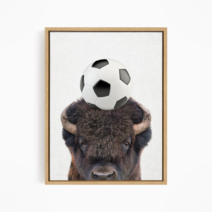 A buffalo with a soccer ball on its head.