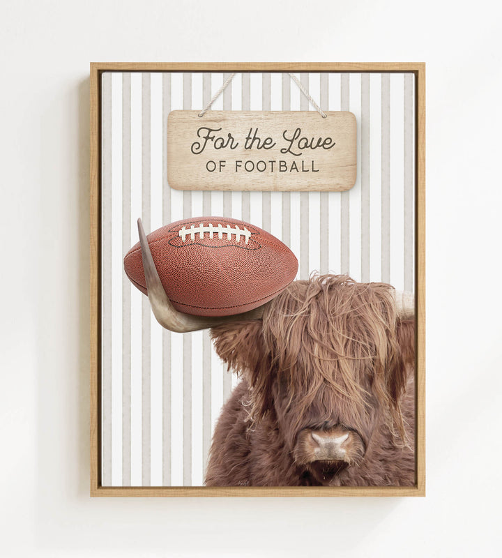 A framed image featuring a Highland cow with a football on its head, accompanied by a wooden sign that reads "For the Love of Football".