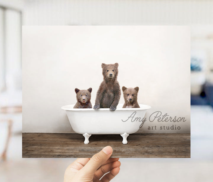 a person holding up a card with three bears in a bathtub