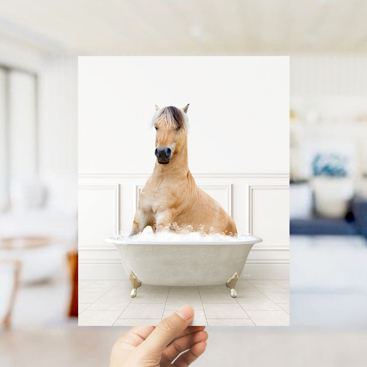 A light brown horse sitting in a white bathtub filled with water, with a blurred background suggesting a bathroom setting.