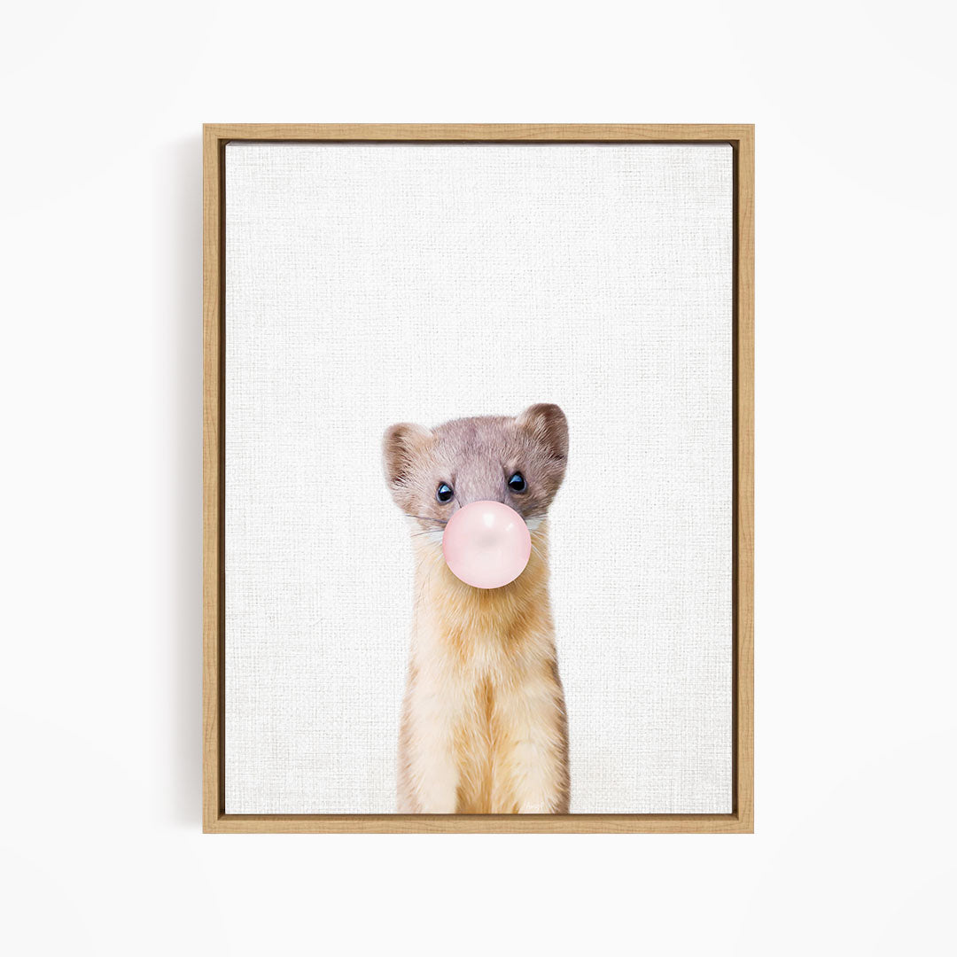 A cute beige and gray ferret is blowing a bubble with a pink bubble gum bubble.