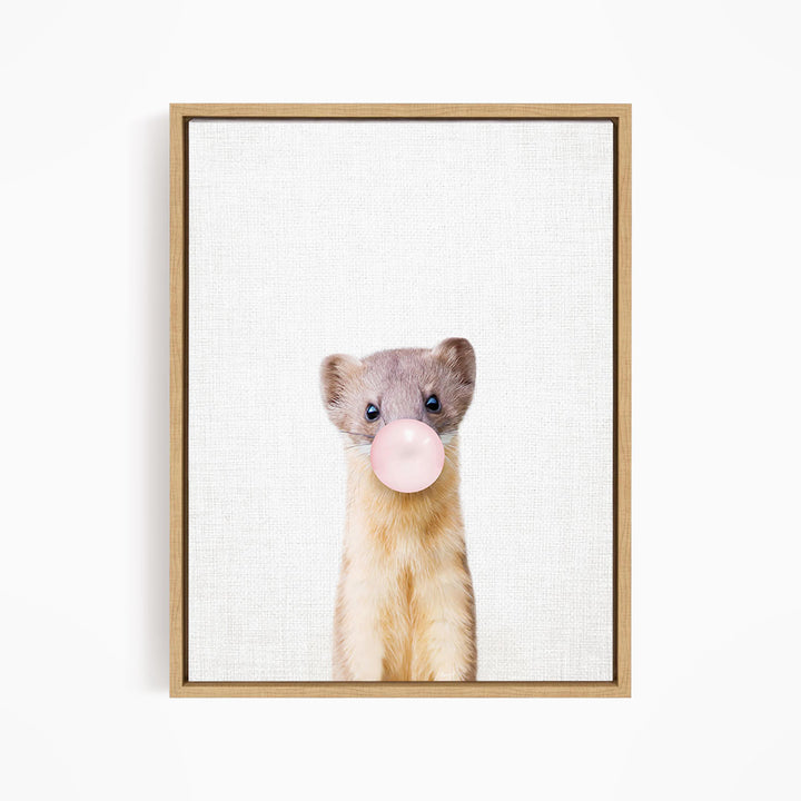 A cute beige and gray ferret is blowing a bubble with a pink bubble gum bubble.