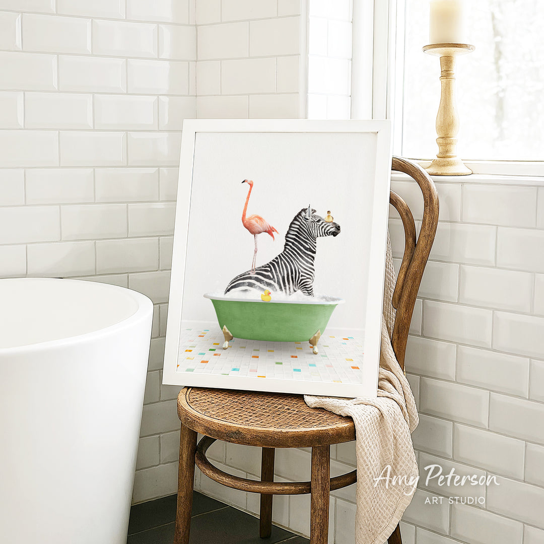 A framed image of a zebra sitting in a green bathtub, with a pink flamingo standing on its back, is displayed on a wooden chair in a bathroom setting.