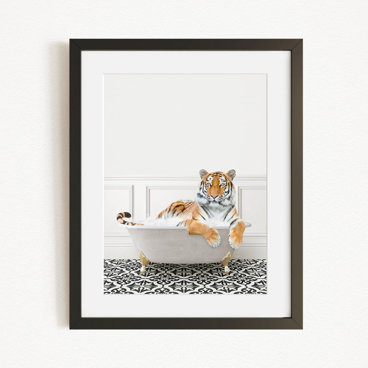 A tiger is sitting in a white bathtub, surrounded by a black and white patterned rug on the floor.