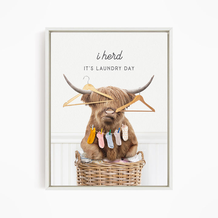 A brown cow with horns sits in a wicker basket, holding clothes on its horns and surrounded by clothes.