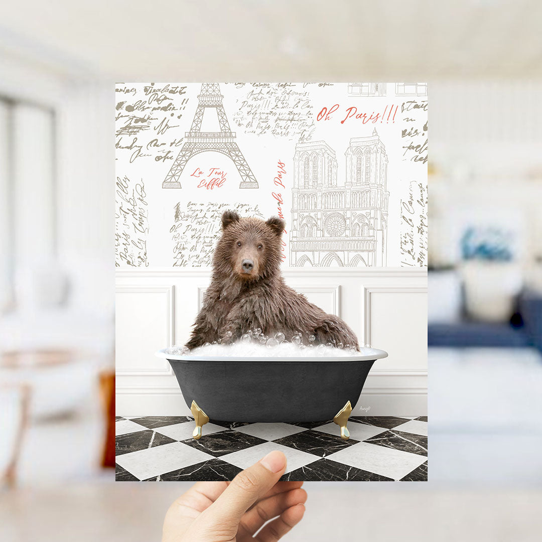 A brown bear sitting in a bathtub filled with bubbles, with the Eiffel Tower and Notre-Dame Cathedral visible in the background.