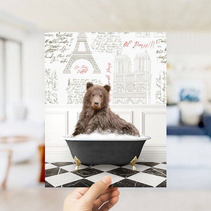 A brown bear sitting in a bathtub filled with bubbles, with the Eiffel Tower and Notre-Dame Cathedral visible in the background.