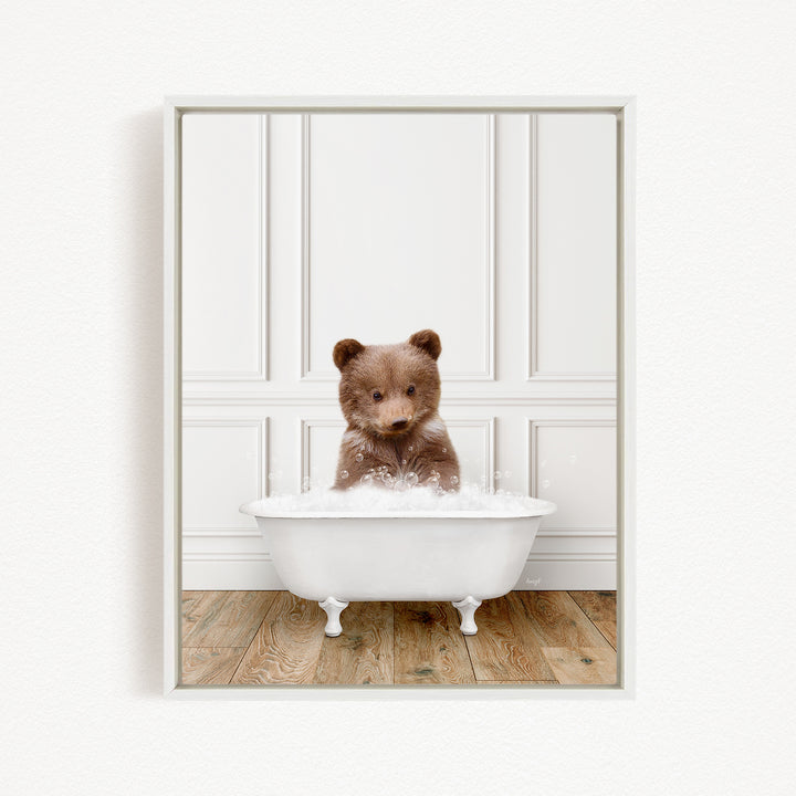 A brown bear sitting in a white bathtub filled with bubbles, looking directly at the camera.