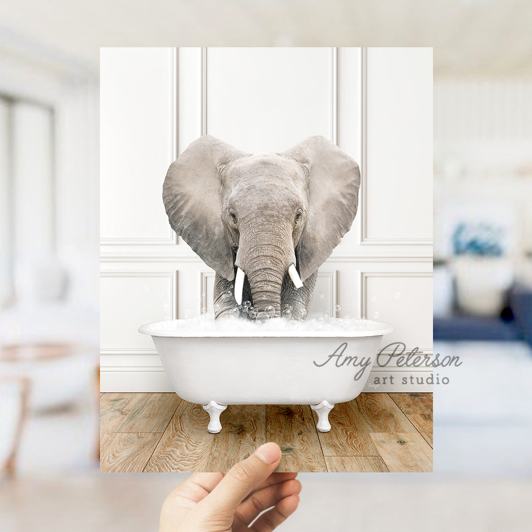 a hand holding a photo of an elephant in a bathtub