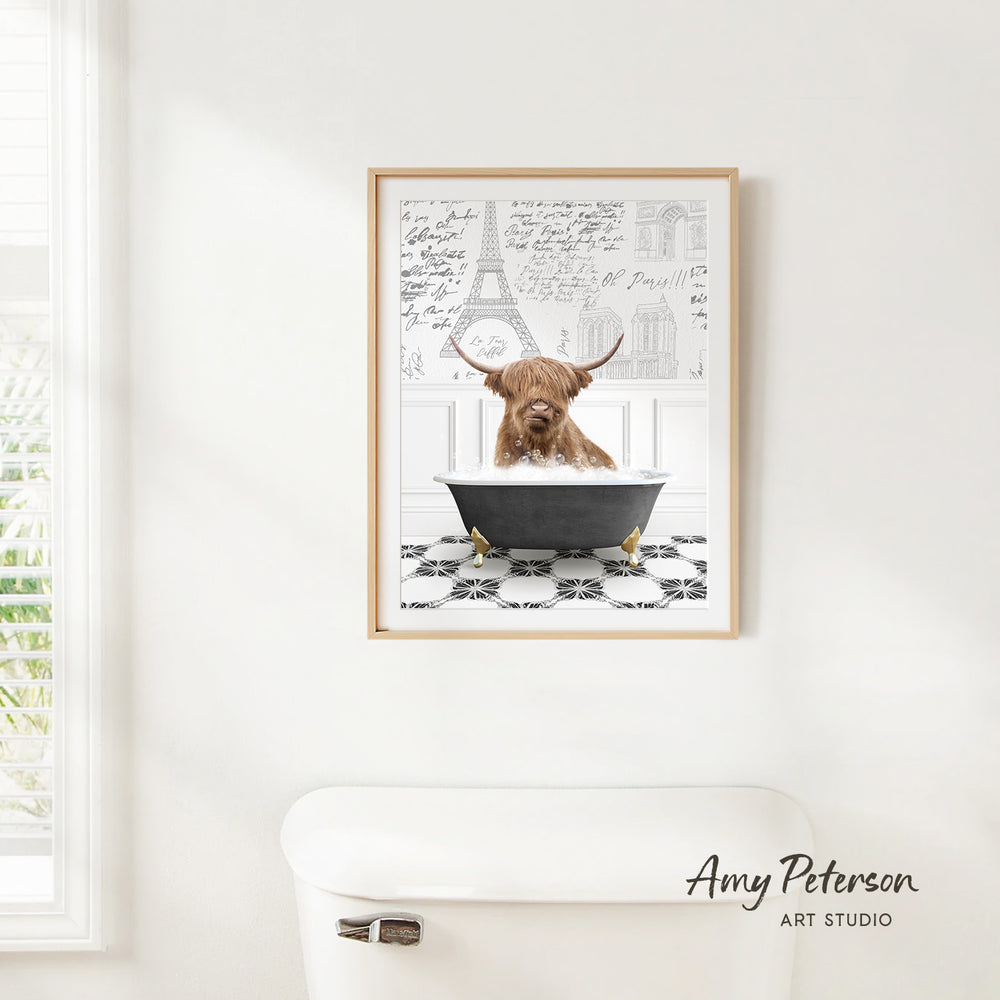 A framed image of a Highland cow sitting in a bathtub, with the Eiffel Tower and other architectural drawings visible in the background.