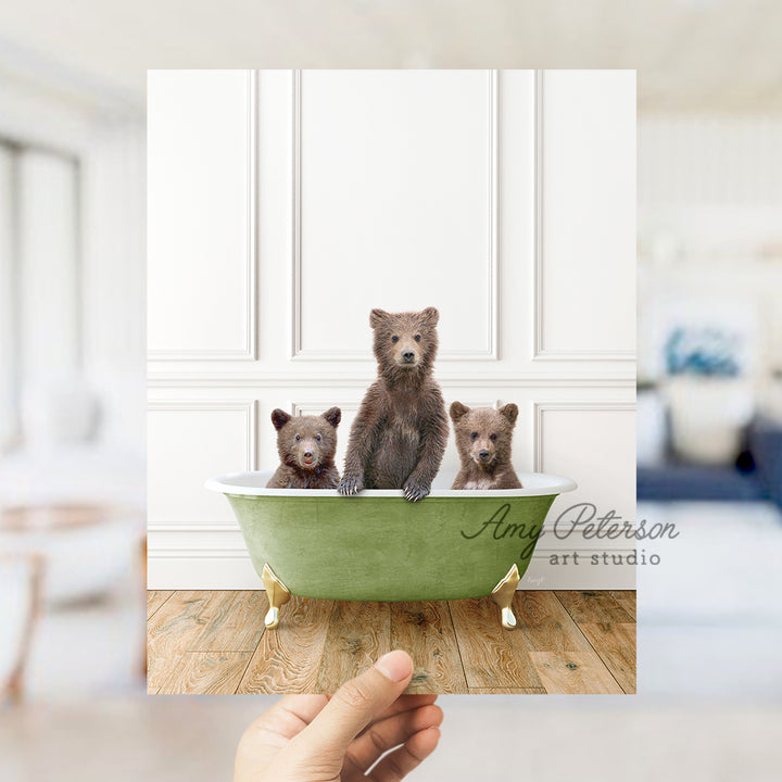 a hand holding a card with three bears in a bathtub