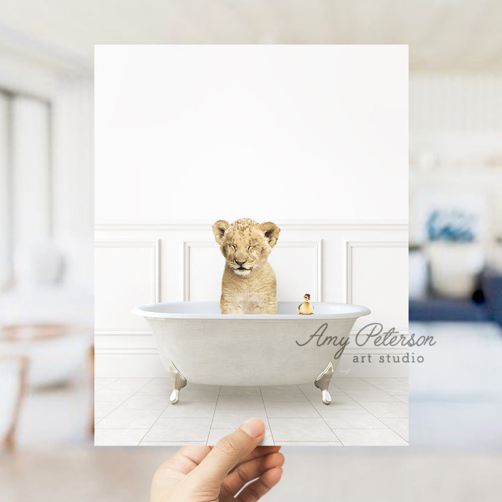 a hand holding a photo of a baby lion in a bathtub