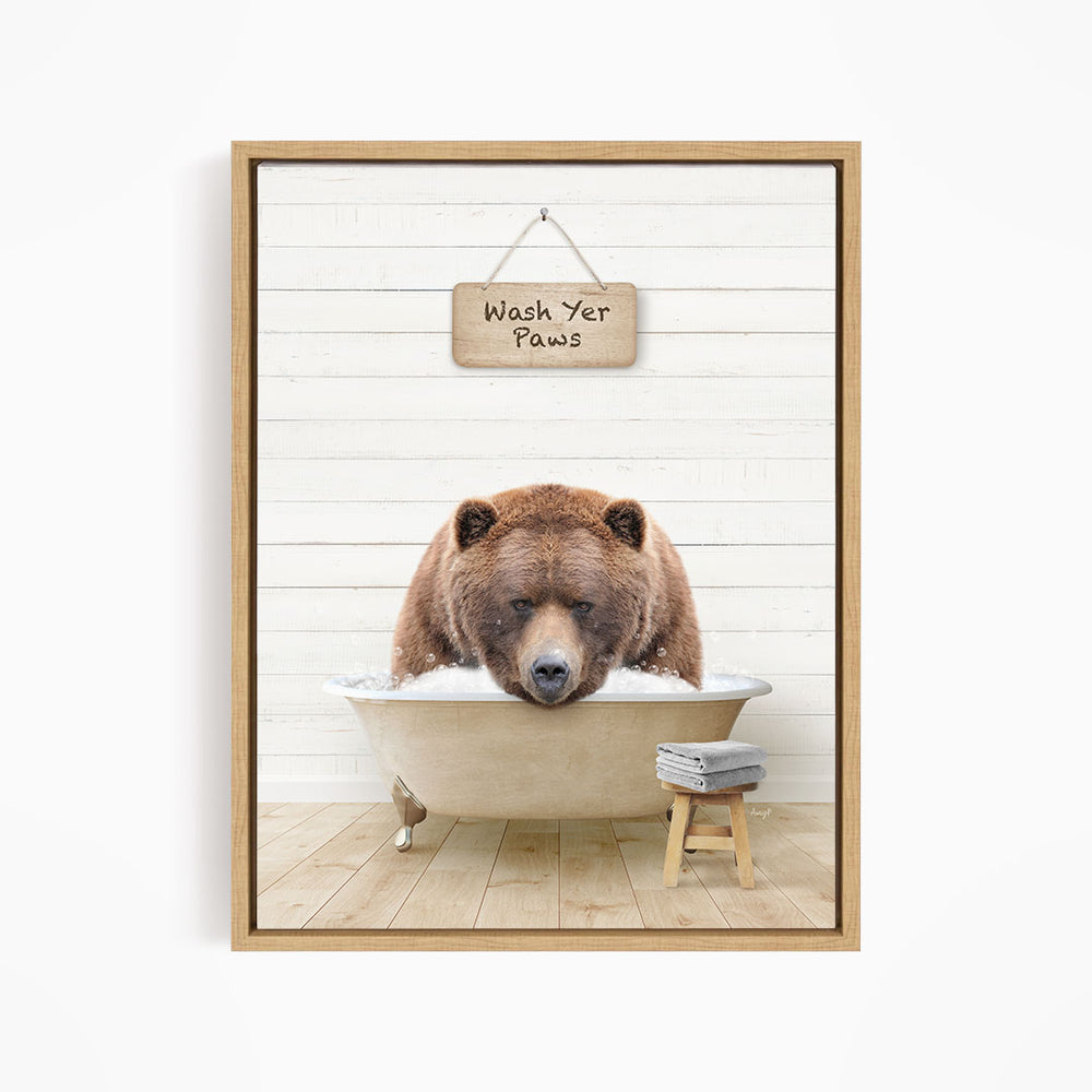 A brown bear is sitting in a bathtub, with a sign above it that says "Wash Your Paws".