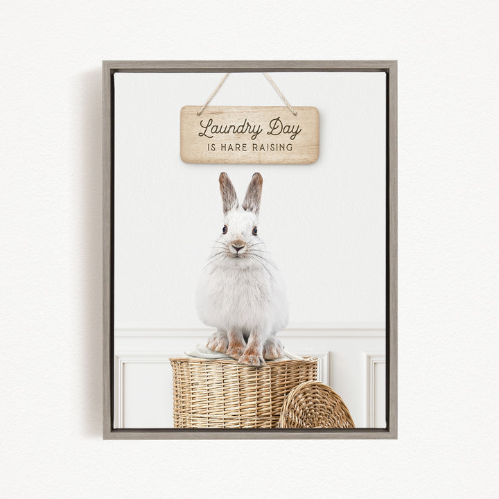 A white rabbit sits on a woven basket, with a wooden sign above that reads "Laundry Day is Hard Raising".
