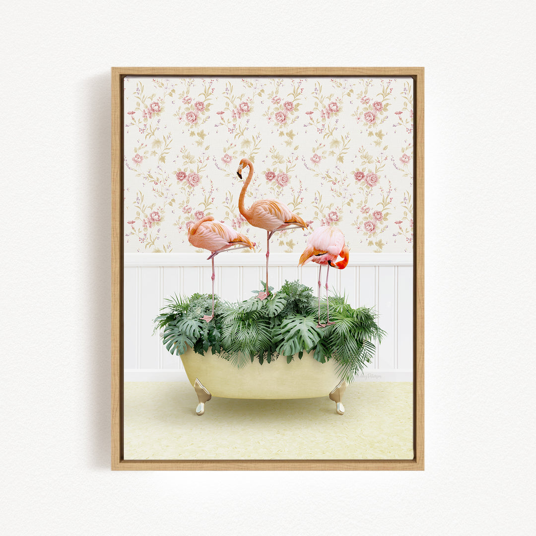 A framed image depicting three flamingos standing in a bathtub filled with green plants, set against a floral wallpaper background.
