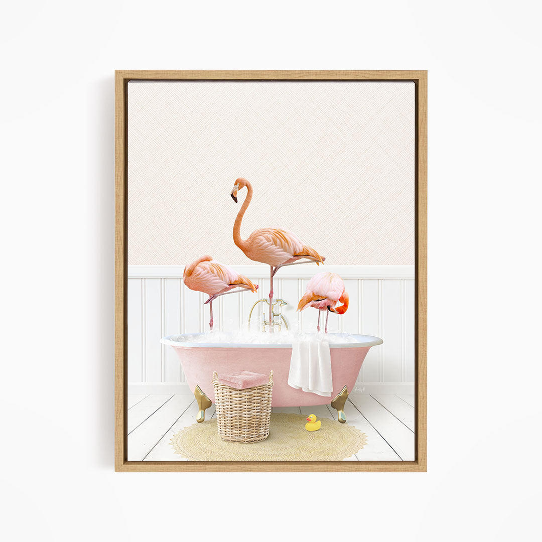 A framed image depicting three flamingos standing in a pink bathtub, with a basket of bath toys and a yellow rubber duck nearby.