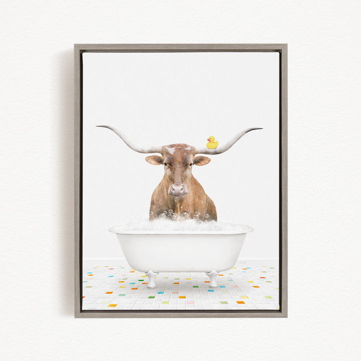 A brown cow with large horns is sitting in a white bathtub filled with bubbles, with a rubber duck floating on the water.