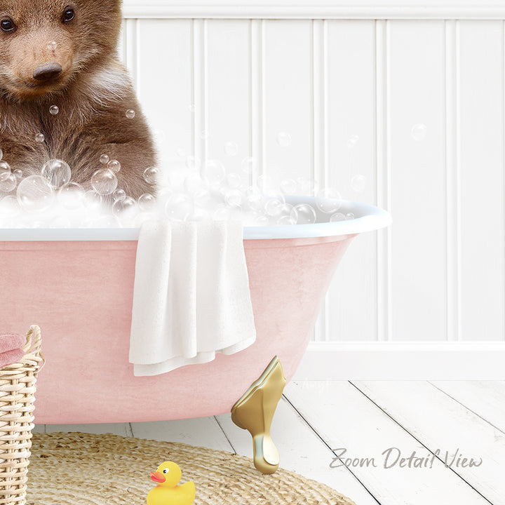 A cute brown bear is sitting in a pink bathtub filled with bubbles, surrounded by a yellow rubber duck and a white towel.