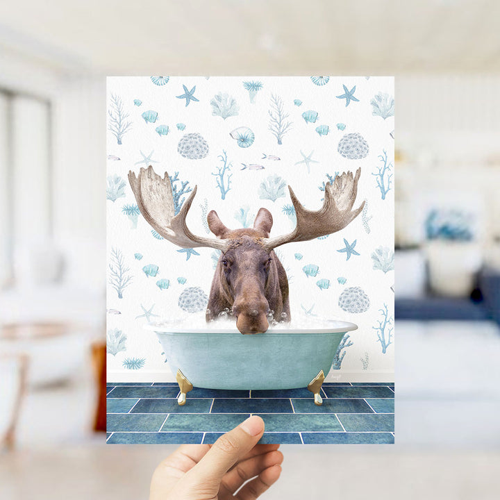 A moose with large antlers is sitting in a bathtub filled with water, surrounded by blue and white marine-themed decorations.