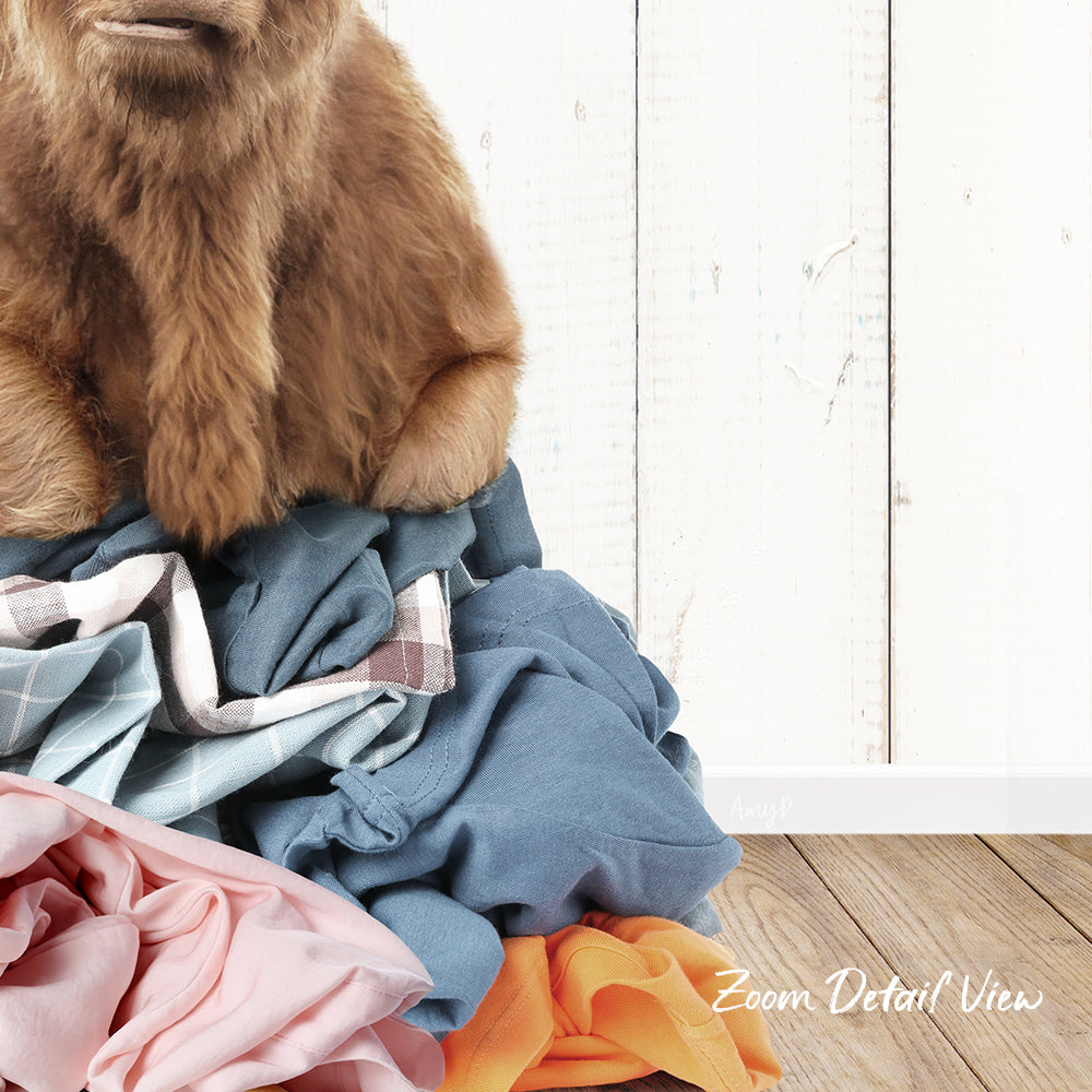 A pile of clothes, including a brown dog sitting on top of the pile, against a white wooden background.