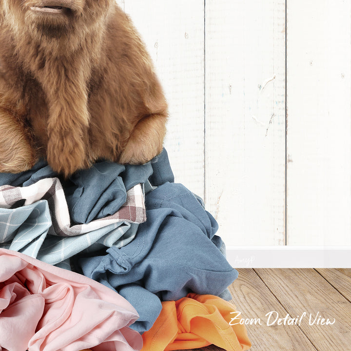 A pile of clothes, including a brown dog sitting on top of the pile, against a white wooden background.