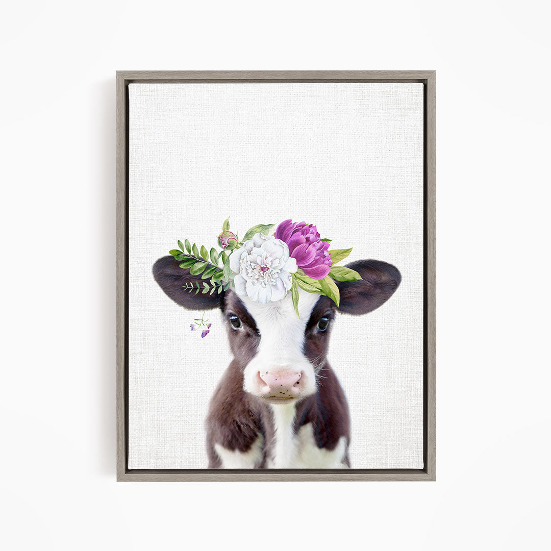A framed print of a cow wearing a floral crown on its head.