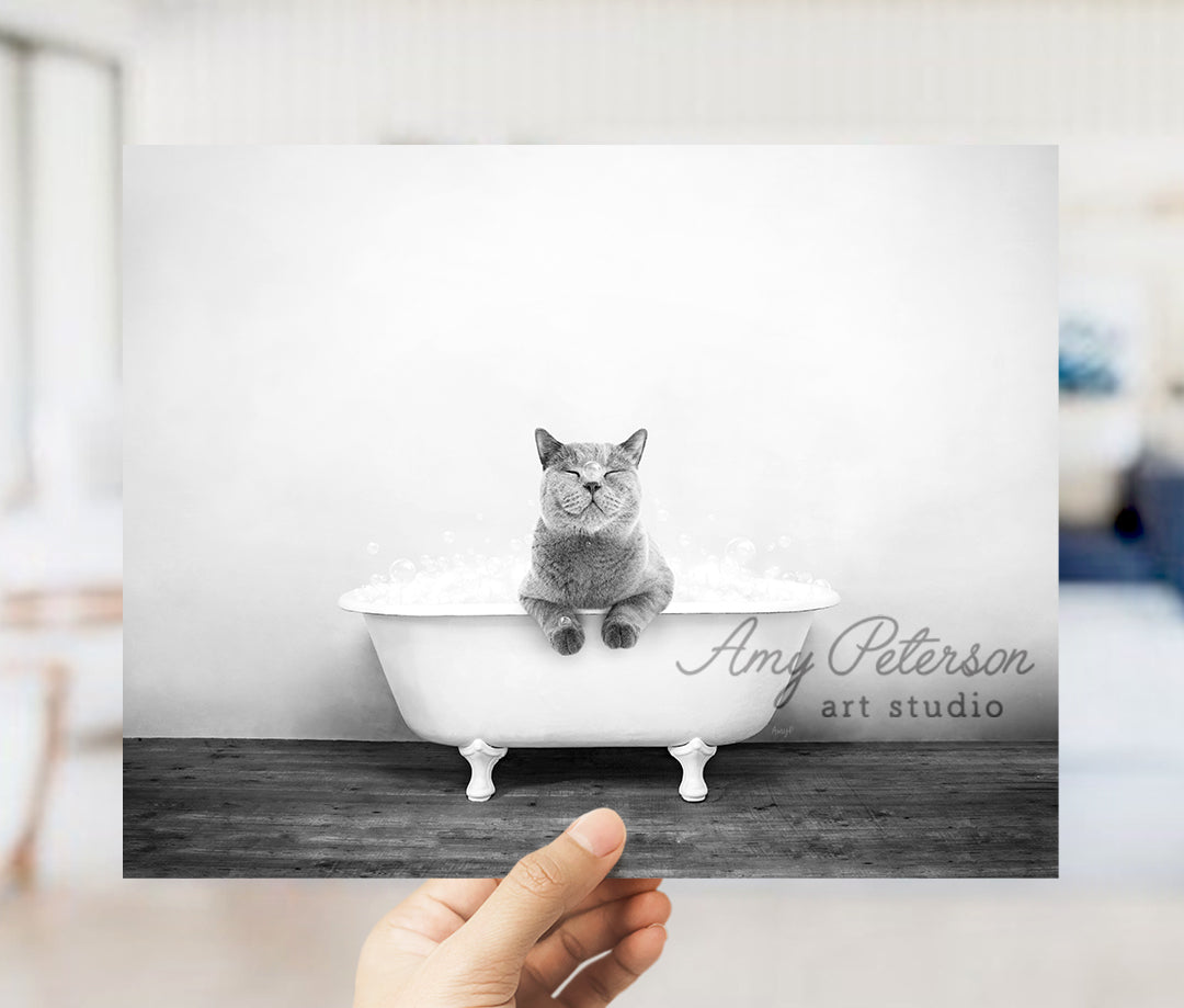 a person holding up a picture of a cat in a bathtub