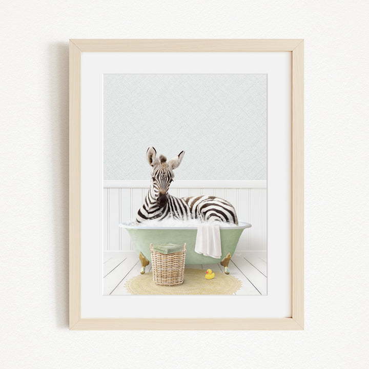 A zebra is sitting in a green bathtub filled with water, surrounded by a basket of toys and a yellow rubber ducky.