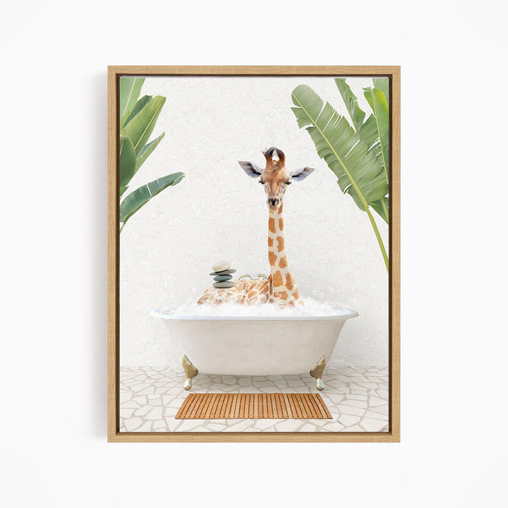 A giraffe is sitting in a bathtub filled with bubbles, surrounded by tropical plants and a wooden mat on the floor.