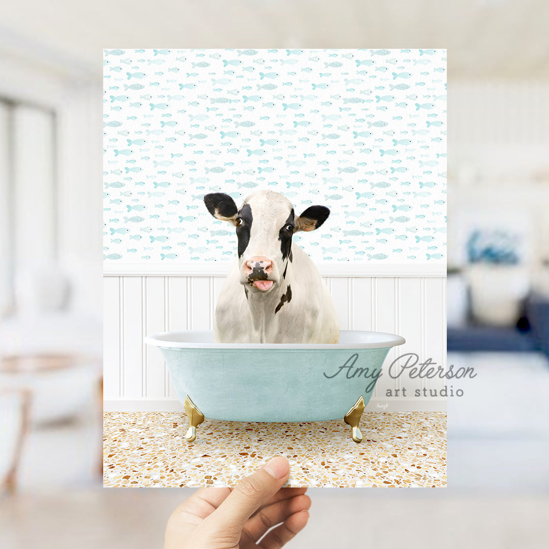 a hand holding up a picture of a cow in a bathtub