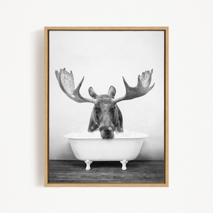 A moose with large antlers is sitting in a bathtub filled with water, creating a whimsical and humorous scene.