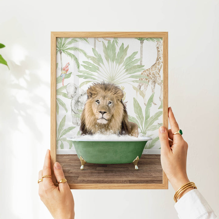 A person's hands are holding a framed picture of a lion sitting in a green bathtub, surrounded by tropical foliage.