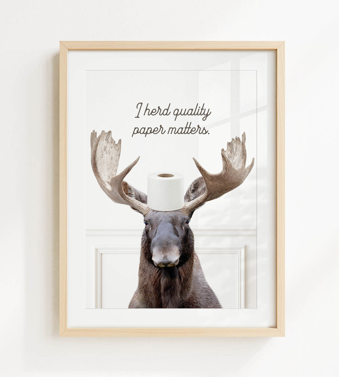 A framed image of a moose with a roll of toilet paper on its head, accompanied by the text "I herd quality paper matters."