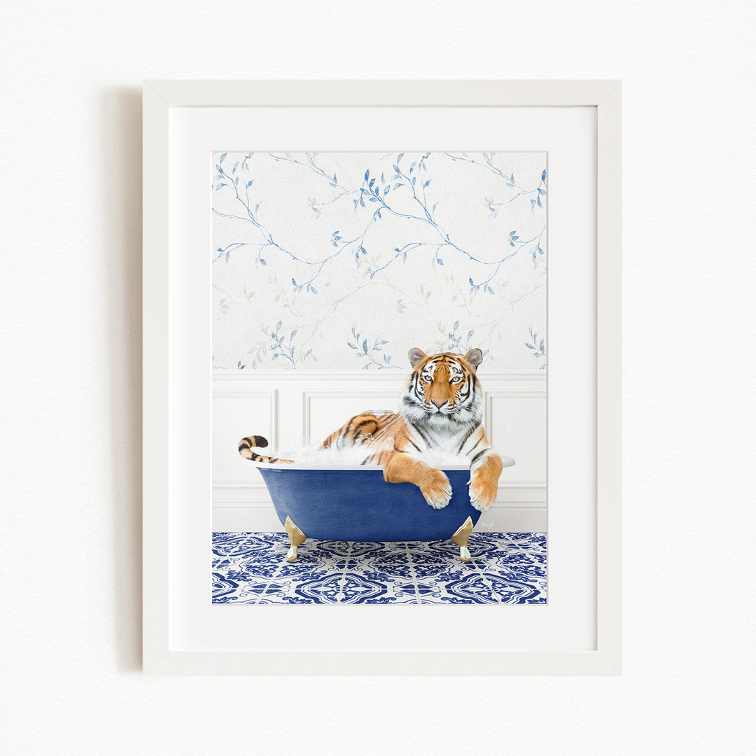 A tiger is sitting in a blue bathtub, surrounded by a blue and white patterned wall and a white floor.