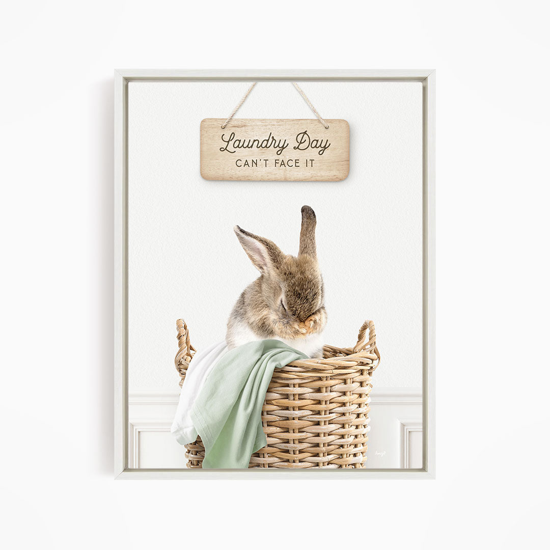 A cute rabbit sitting in a wicker basket, with a wooden sign above that says "Laundry Day Can't Face It".