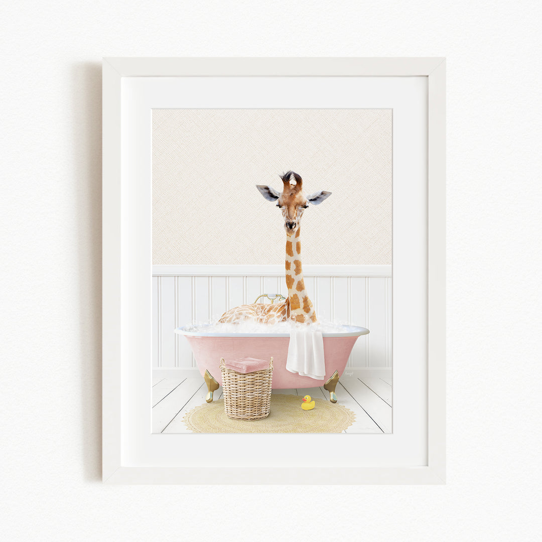 A giraffe is sitting in a pink bathtub filled with water, surrounded by a yellow rubber duck and a basket.