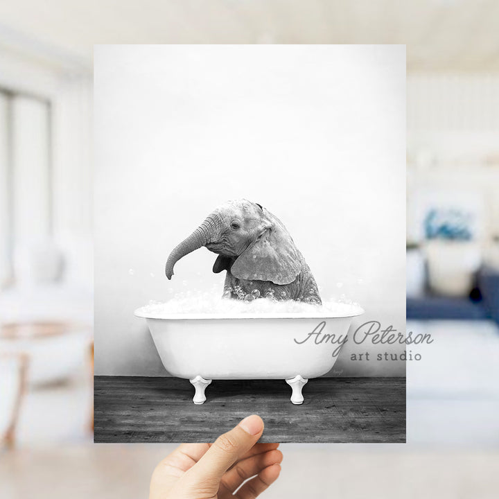 a person holding up a picture of an elephant in a bathtub