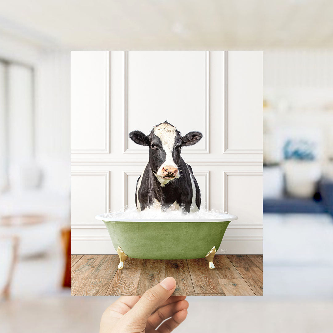 A black and white cow is sitting in a green bathtub filled with water, creating a humorous and whimsical scene.