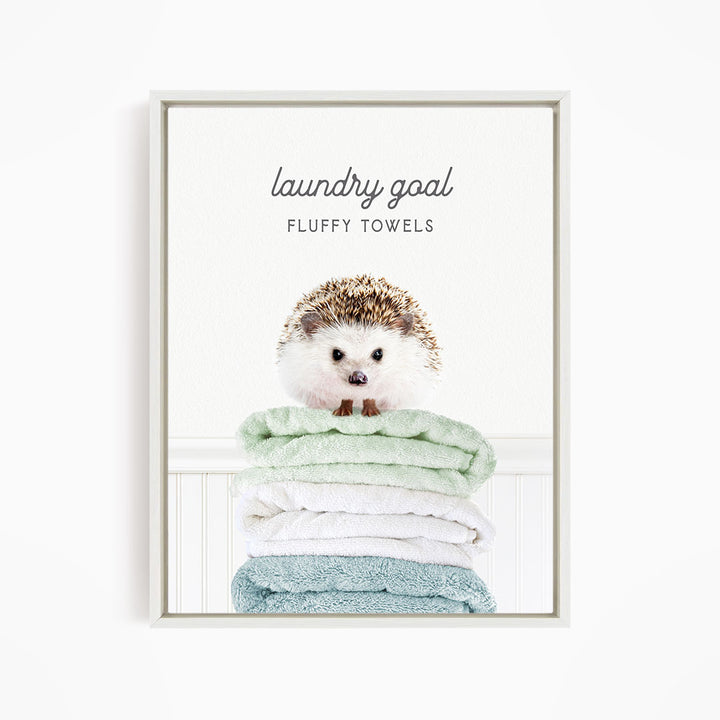 A cute hedgehog sitting atop a stack of fluffy towels, with the text "laundry goal FLUFFY TOWELS" displayed above it.