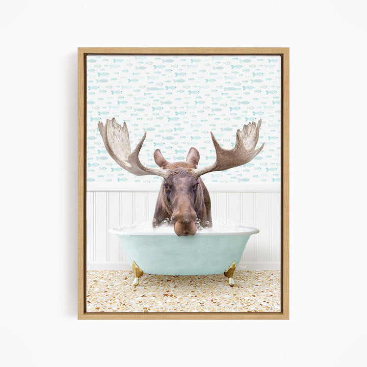 A moose with large antlers is sitting in a light blue bathtub, surrounded by a patterned tile floor and a white wall with a blue and white fish wallpaper.