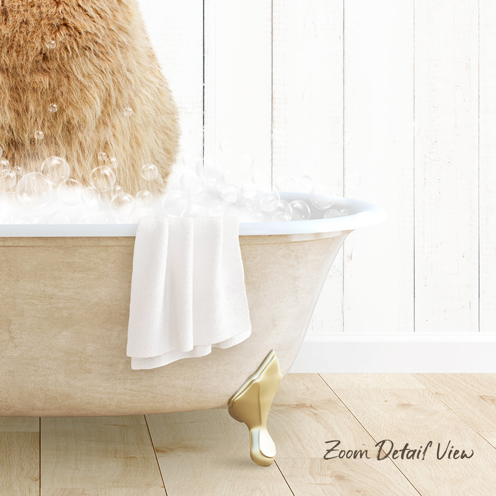A fluffy brown cat sitting in a bathtub filled with bubbles, with a towel and gold bathtub leg visible.