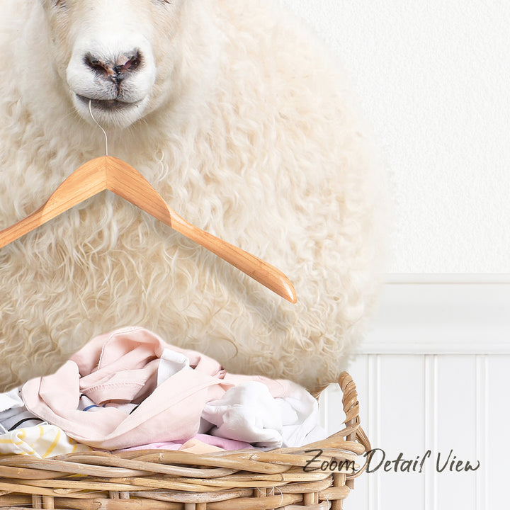 A fluffy white sheep is standing behind a wicker basket filled with clothes, with a wooden hanger attached to the basket.