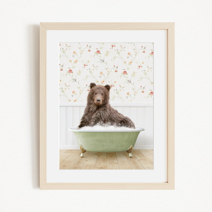 A brown bear sitting in a green bathtub filled with bubbles, with a floral wallpaper in the background.