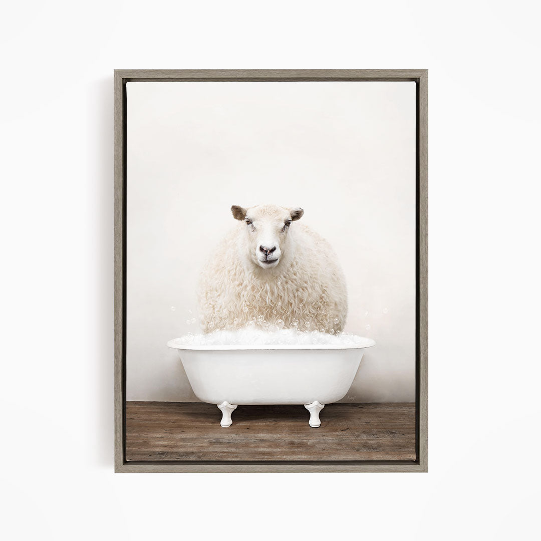 A fluffy white sheep sits in a white bathtub filled with bubbles, looking directly at the camera.