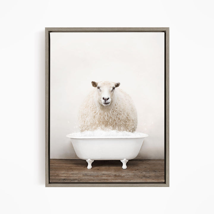 A fluffy white sheep sits in a white bathtub filled with bubbles, looking directly at the camera.