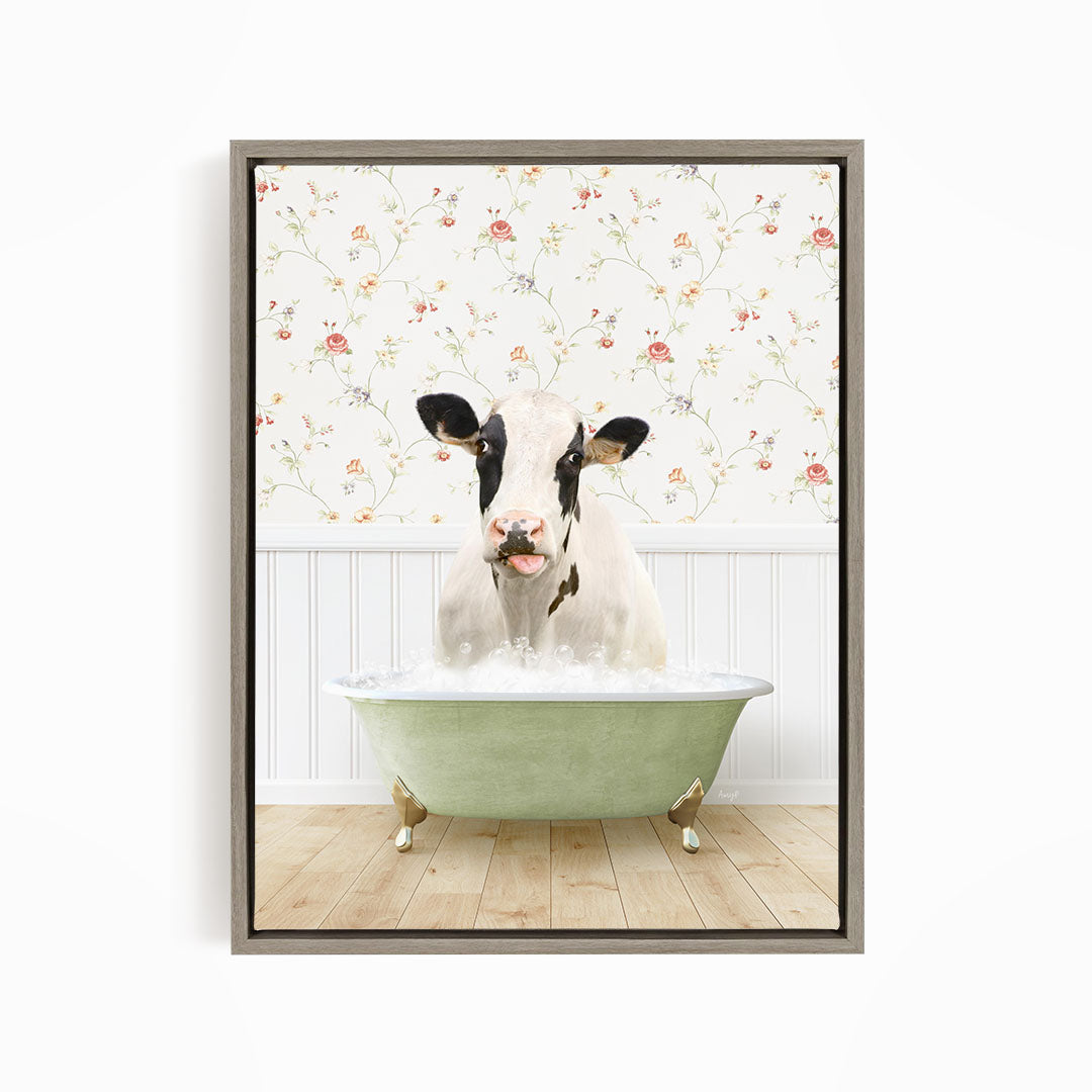 A black and white cow is sitting in a green bathtub filled with water, with a floral wallpaper in the background.